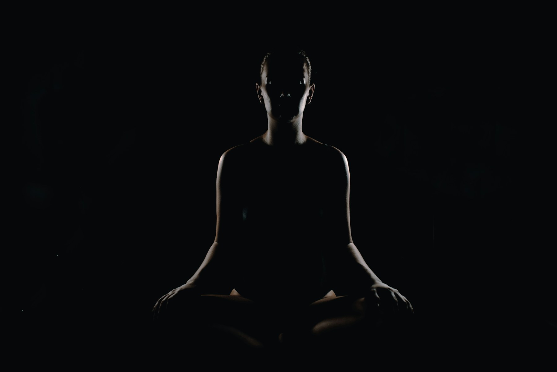 Person seated in a meditation pose against a neutral background